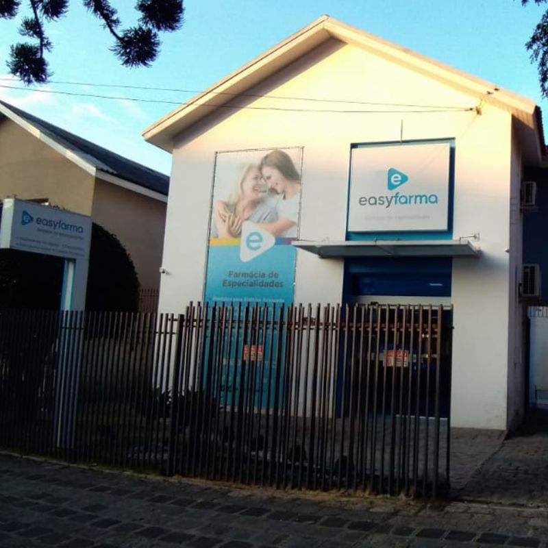 Fachada da Farmácia de Especialidades Easyfarma, casa branca com placa azul do logotipo.